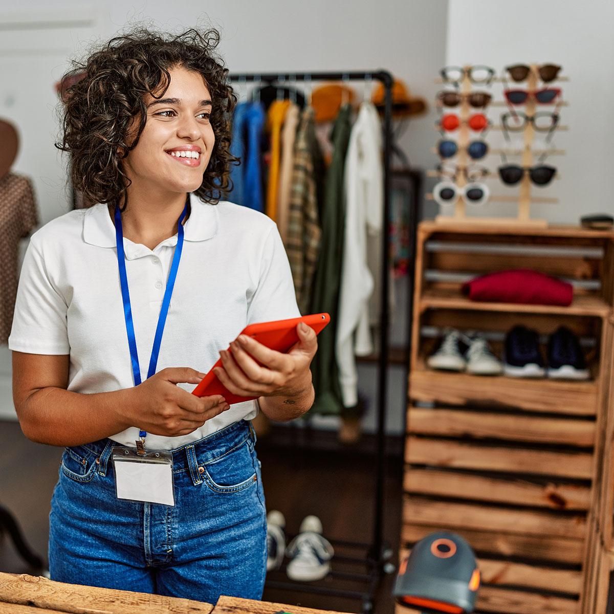 Young latin shopkeeper woman using touchpad working at clothing store.